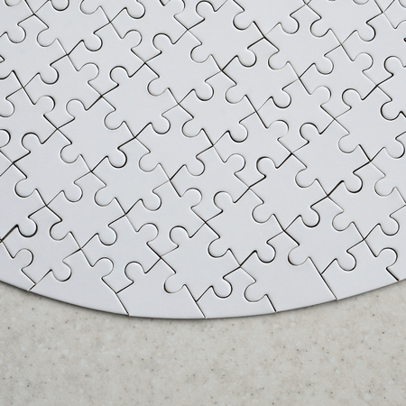 A white jigsaw puzzle in the complete form lies on a treated stone surface. Textured image with copy spaceの写真素材