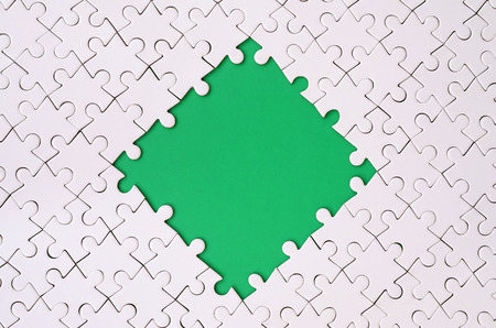 Framing in the form of a rhombus, made of a white jigsaw puzzle around the green space