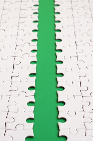 The green path is laid on the platform of a white folded jigsaw puzzle. Texture image with copy space for textの写真素材