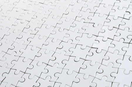 Close up of a white jigsaw puzzle in assembled state in perspective. Many components of a large whole mosaic are unitedの写真素材