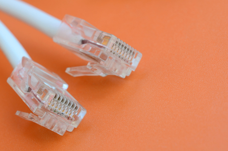 White cord with connector rj45 on a bright orange background. network ethernet cable plugsの写真素材