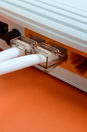 The Internet cable plugs are connected to the Internet router, which lies on a bright orange background. Items required for Internet connectionの写真素材