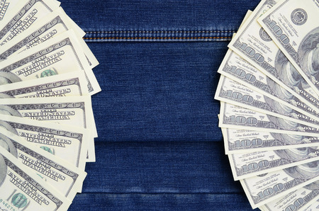 The fan of a lot of US dollars is on a dark denim surface. Background imageの写真素材
