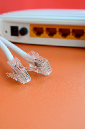 Internet router and Internet cable plugs lie on a bright orange background. Items required for...