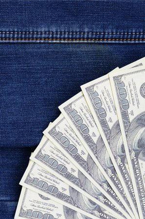 The fan of a lot of US dollars is on a dark denim surface. Background imageの写真素材