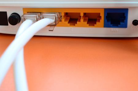 The Internet cable plugs are connected to the Internet router, which lies on a bright orange...
