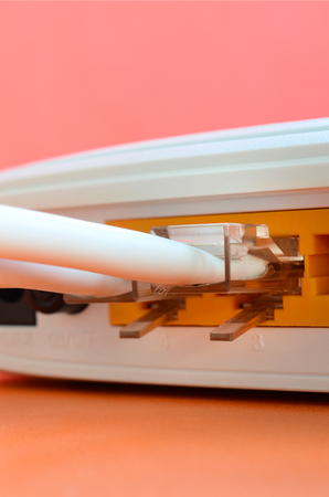The Internet cable plugs are connected to the Internet router, which lies on a bright orange background. Items required for Internet connectionの写真素材