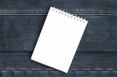 White notebook with clean pages lying on dark blue jeans background. Image with copy spaceの写真素材