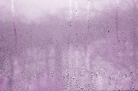Texture of a drop of rain on a glass wet transparent background. Toned in pink colorの写真素材