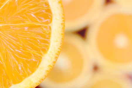Top view of a fragment of the orange fruit slice on the background of many blurred orange slices. A...