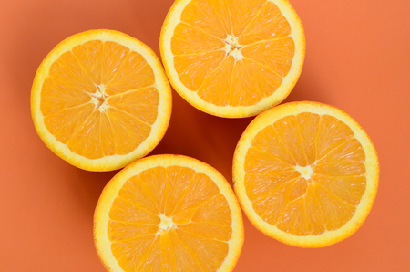 Top view of a several orange fruit slices on bright background in orange color. A saturated citrus texture imageの写真素材