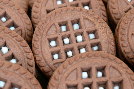 Detailed picture of dark brown round sandwich cookies with coconut filling close up. Background...