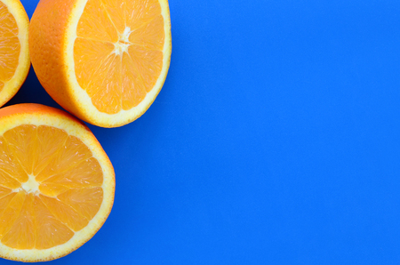 Top view of a several orange fruit slices on bright background in blue color. A saturated citrus texture imageの写真素材