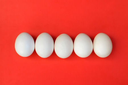 A few white eggs on a bright red backgroundの写真素材