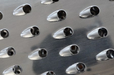 A fragment of a metal chrome grater close-up. Texture of blades for grinding foodの写真素材