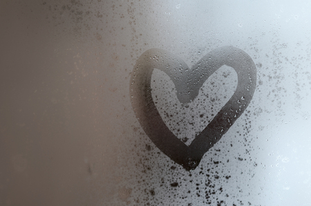 The heart is painted on the misted glass in the winterの写真素材