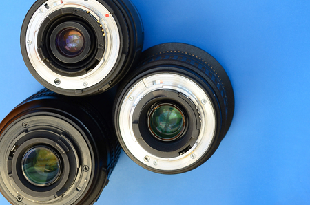 Several photographic lenses lie on a bright blue background. Space for textの写真素材