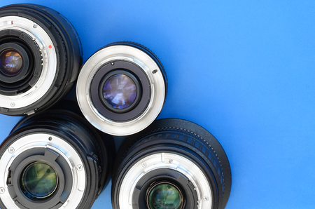 Several photographic lenses lie on a bright blue background. Space for textの写真素材