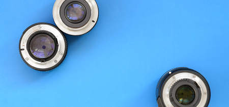 Several photographic lenses lie on a bright blue background. Space for textの写真素材