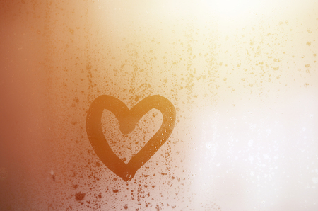 The heart is painted on the misted glass in the winterの写真素材