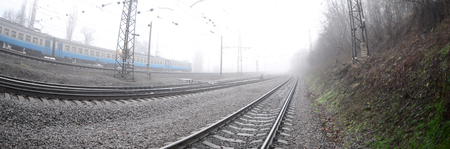 The Ukrainian suburban train rushes along the railway in a misty morning. Fisheye photo with...