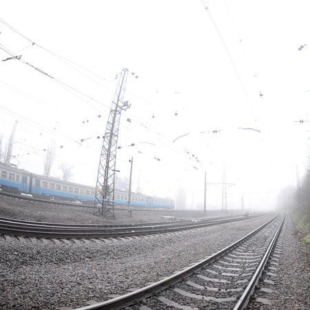 The Ukrainian suburban train rushes along the railway in a misty morning. Fisheye photo with increased distortionの写真素材