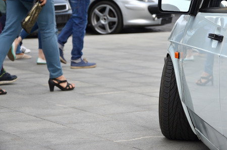 Diagonal view of a white glossy car that stands on a square of gray tiles