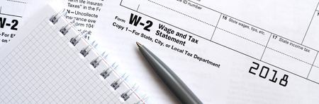 The pen and notebook on the tax form W-2 Wage and Tax Statement. The time to pay taxes