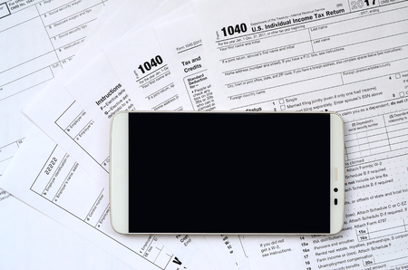 The smartphone lies on the tax form 1040 and W-2. Clean black screen smartphone for text placementの写真素材