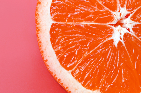 Top view of a one grapefruit slice on bright background in light pink color. A saturated citrus texture imageの写真素材