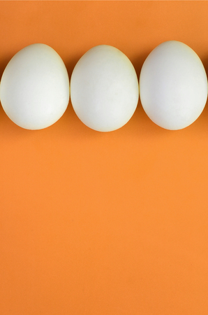 A few white easter eggs on a bright orange background