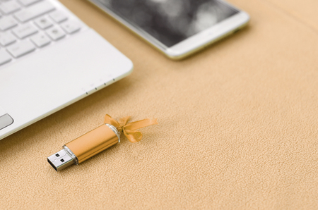 Orange usb flash memory card with a blue bow lies on a blanket of soft and furry light orange fleece...