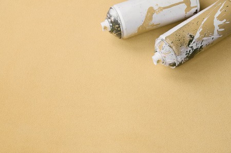 Some used blue aerosol spray cans with paint drips lies on a blanket of soft and furry light blue fleece fabric. Classic female design color. Graffiti hooliganism conceptの写真素材