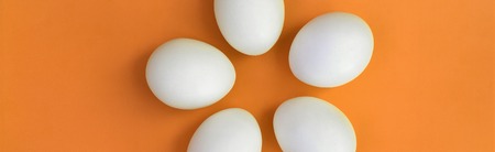 A few white easter eggs on a bright orange backgroundの写真素材