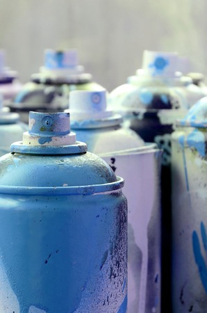 A lot of dirty and used aerosol cans of bright blue paint. Macro photograph with shallow depth of field. Selective focus on the spray nozzleの写真素材