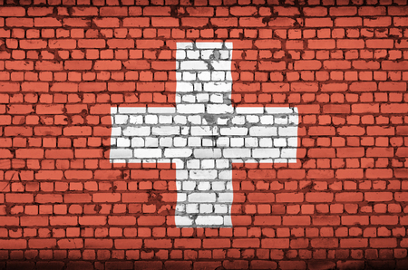 Switzerland flag is painted onto an old brick wallの写真素材