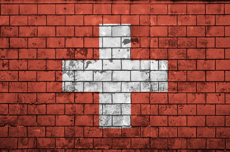 Switzerland flag is painted onto an old brick wallの写真素材