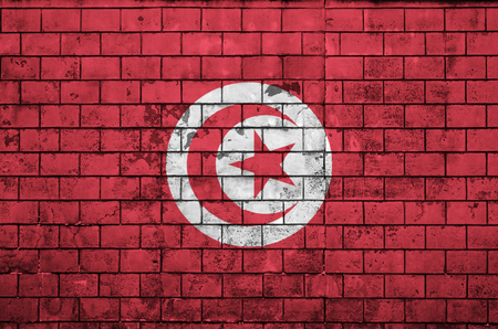Tunisia flag is painted onto an old brick wallの写真素材