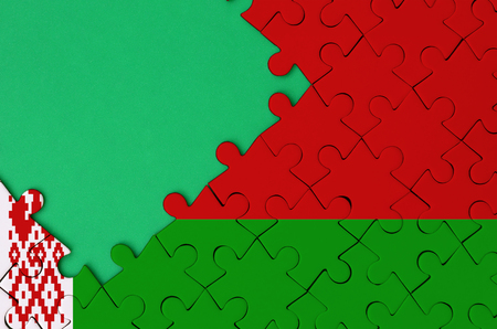 Belarus flag  is depicted on a completed jigsaw puzzle with free green copy space on the left side.の写真素材