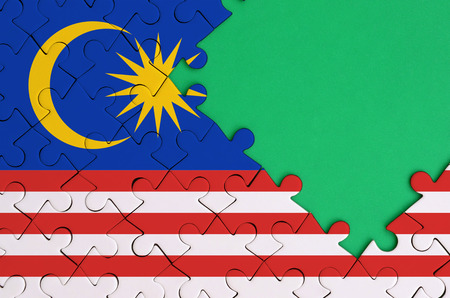 Malaysia flag  is depicted on a completed jigsaw puzzle with free green copy space on the right side.の写真素材
