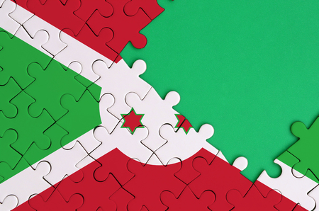 Burundi flag  is depicted on a completed jigsaw puzzle with free green copy space on the right side.の写真素材