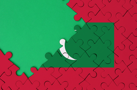Maldives flag  is depicted on a completed jigsaw puzzle with free green copy space on the left side.の写真素材