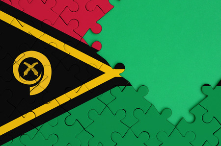 Vanuatu flag  is depicted on a completed jigsaw puzzle with free green copy space on the right side.の写真素材