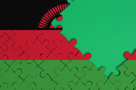 Malawi flag  is depicted on a completed jigsaw puzzle with free green copy space on the right side.の写真素材
