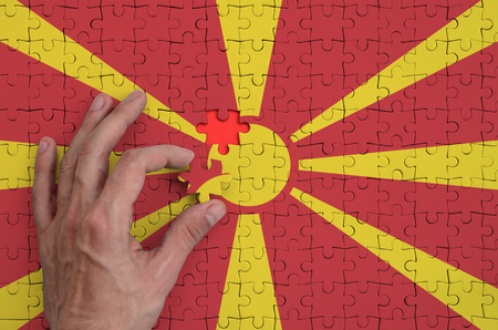 Macedonia flag  is depicted on a puzzle, which the man's hand completes to fold.の写真素材