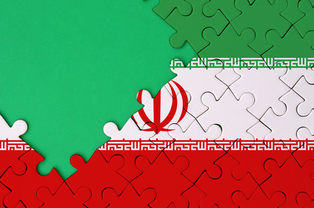Iran flag  is depicted on a completed jigsaw puzzle with free green copy space on the left side.の写真素材