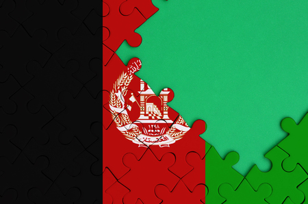 Afghanistan flag is depicted on a completed jigsaw puzzle with free green copy space on the right side.の写真素材