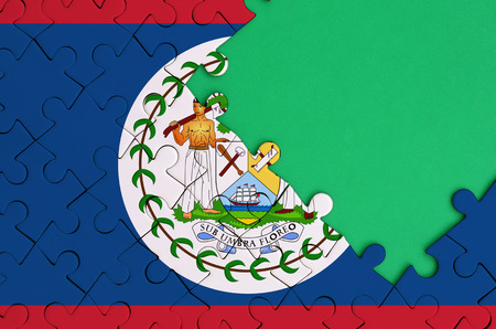 Belize flag  is depicted on a completed jigsaw puzzle with free green copy space on the right side.の写真素材