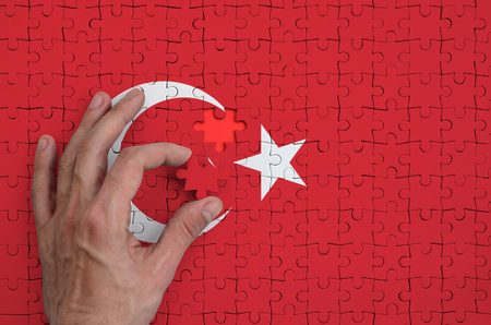 Turkey flag  is depicted on a puzzle, which the man's hand completes to fold.の写真素材