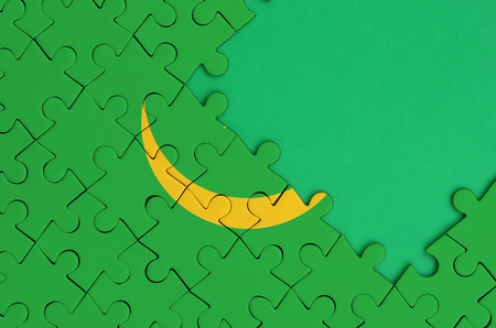 Mauritania flag  is depicted on a completed jigsaw puzzle with free green copy space on the right side.の写真素材